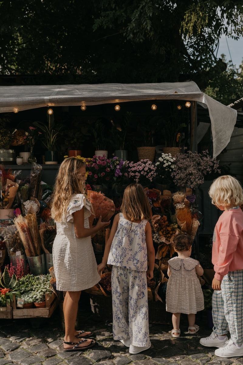 Kinder tragen diverse Kleidung und auch hier sieht man die Culottes aus weichem Baumwoll-Musselin in Beige mit gepolstertem, verstellbarem Gummizug, dekorativer Rüsche und Seitentaschen – unisex und knöchellang.