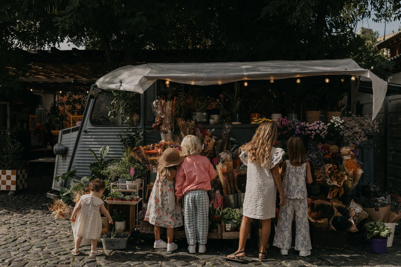 Kinder in bunten Sommer-Outfits darunter Culottes aus weichem Baumwoll-Musselin in Beige mit gepolstertem, verstellbarem Gummizug, dekorativer Rüsche und Seitentaschen – unisex und knöchellang.