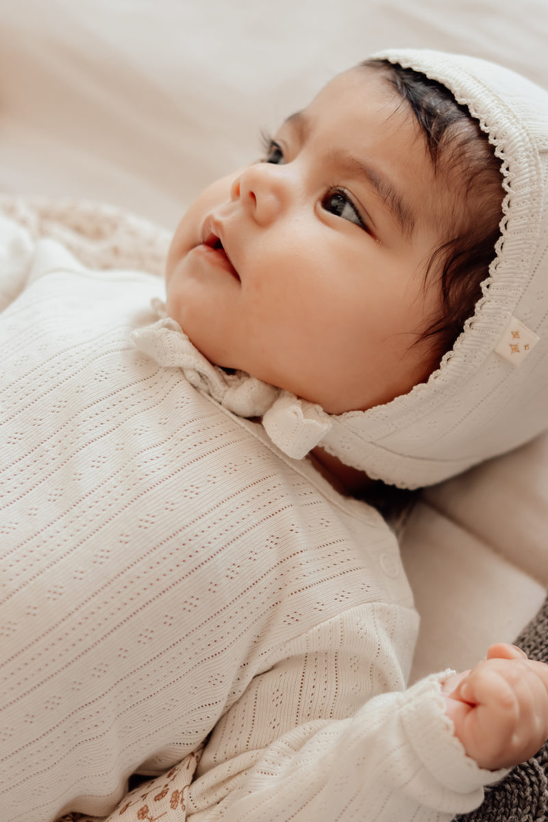 Anna Babymützchen mit Schnüren am Kinn für eine perfekte Passform. Baby in Mütze in Farbe Antique Weiss.