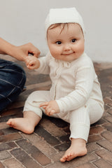 Baby sitzt auf dem Boden, hat Baby Anna Mützchen an. 