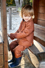 Thermo-Set aus recyceltem Polyester - Junior. Das Thermoset ist ideal unter Regenkleidung. Kind trägt Thermo Anzug beim Spielen. 