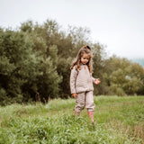 Thermo-Set aus recyceltem Polyester - Junior. Mädchen trägt Outdoor-Set drausen beim Spielen. Das Thermoset ist ideal unter Regenkleidung.