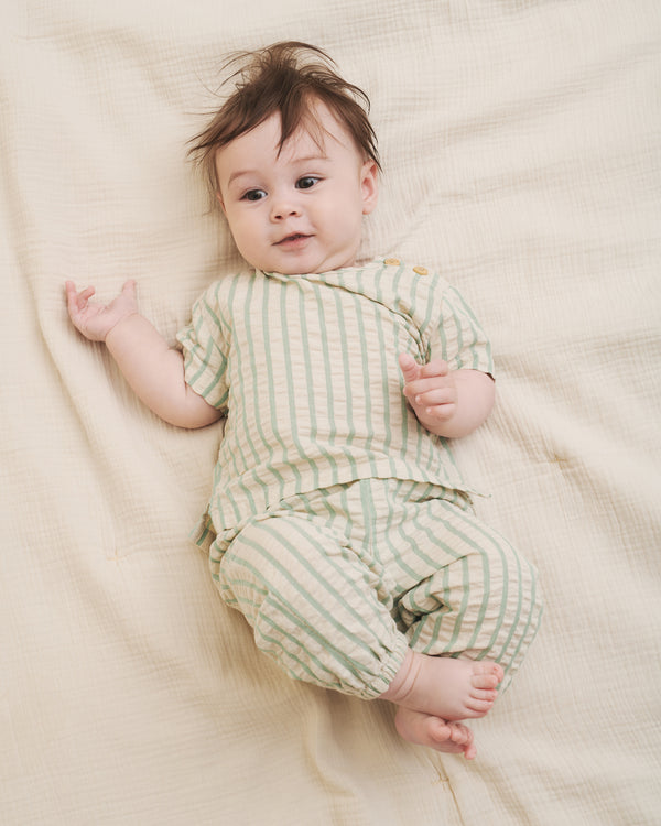 Baby liegend in einem bequemen Sommer Outfit aus Kurzarm Shirt und luftig geschnittener Hose, Pumphose im Stil. Mit Gummizug an den Beinenden. Bio Baumwolle. 