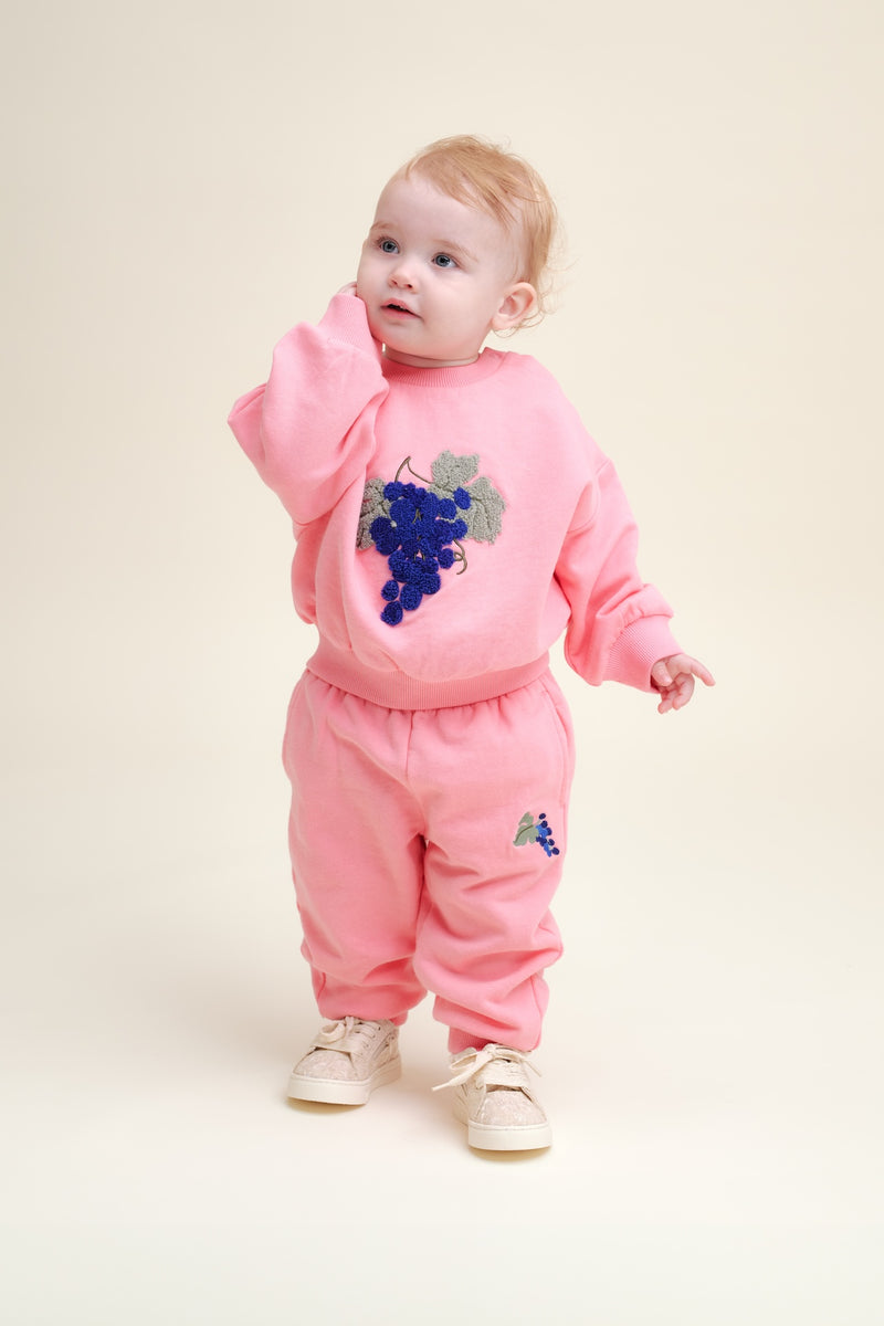 Baby trägt Kinder-Sweathose aus weicher Bio-Baumwolle mit dezenter Stickerei, handgezeichnetem Print, Seitentaschen, elastischen Bündchen & Kordelzug-Bund.