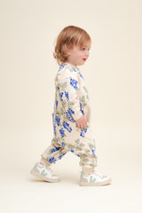 Kleinkind trägt Baby-Onesie aus weicher Bio-Baumwolle mit handgezeichnetem Print, gebürsteter Innenseite, Rippbündchen und Druckknöpfen an Schulter, Schritt & Beinen. Seitenprofil

