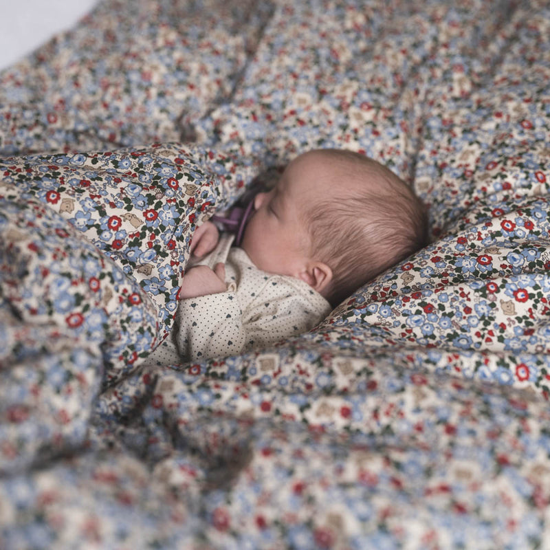 Baby eingehüllt in feinste Wäsche. Kuscheliges Musselin Wickeltuch aus 100% Bio-Baumwolle, 120x120 cm, für Geborgenheit und Komfort mit einem wunderschönen Muster - kleine Hasen auf einem Blumenfeld.